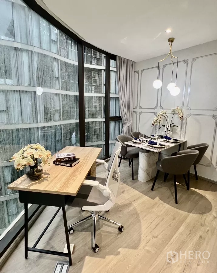 Condominium for rent in Khlong Toei, Bangkok - Dining and work area by a panoramic curved window with desk and pendant lights.