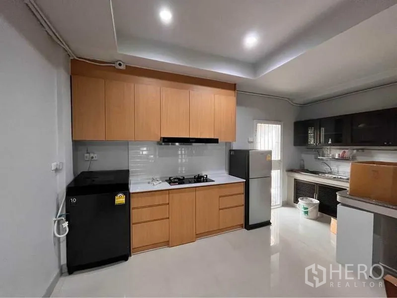 Townhouse for rent in Khlong Toei, Bangkok - Fitted kitchen with wood cabinetry, gas hob, fridge and secondary stainless sink.