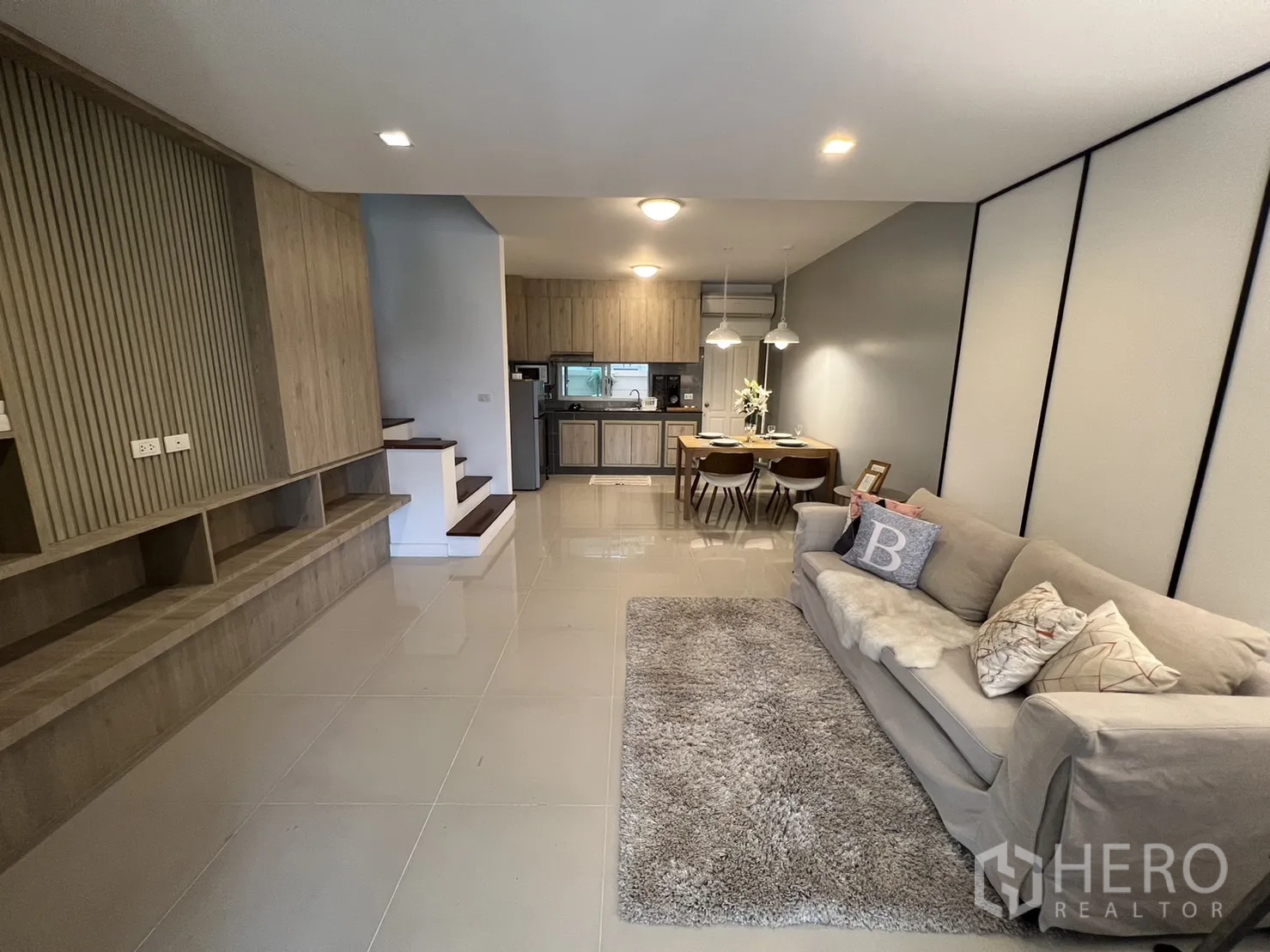 联排别墅 for rent in Suan Luang, Bangkok - 开放式客厅，配沙发与地毯，连通餐区与整体厨房。
