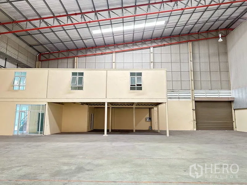 Factory for rent in Bang Phli, Samut Prakan - Warehouse interior showing mezzanine office block, roller shutter door and red steel roof trusses.