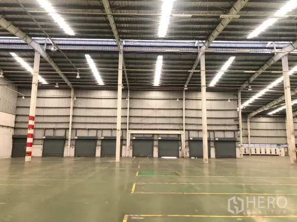 Factory for rent in Phra Nakhon Si Ayutthaya - Interior view toward loading dock doors under bright strip lighting inside the warehouse.
