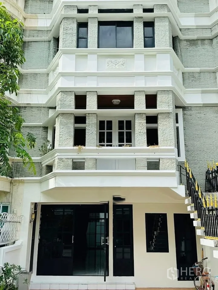 Townhouse for rent - Front facade of a multi-storey townhouse with balconies and black-framed doors.