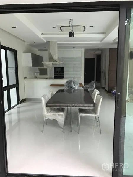 Detached House for rent in Bang Kapi, Bangkok - View through sliding doors to sleek dining area and white fitted kitchen with ceiling cassette AC.