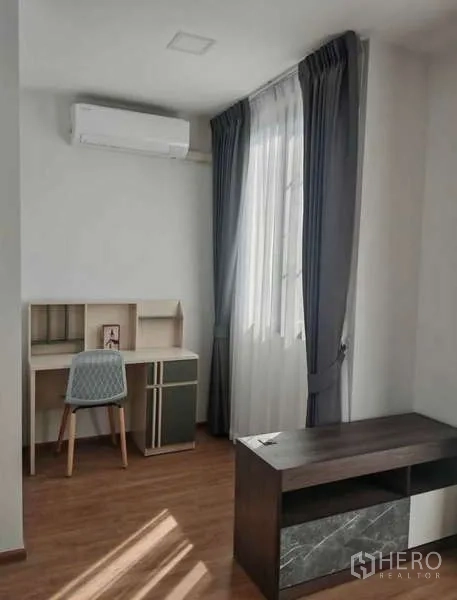 Townhouse for rent in Bang Phli, Samut Prakan - Study or third bedroom with desk, chair, dark TV console, window and air conditioner.