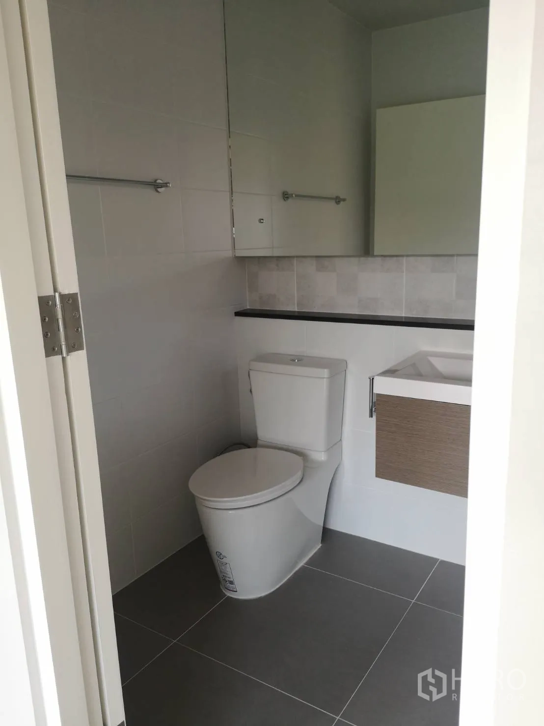 Detached House for sale in Lam Luk Ka, Pathum Thani - Clean white bathroom with toilet, vanity cabinet and a large mirror.