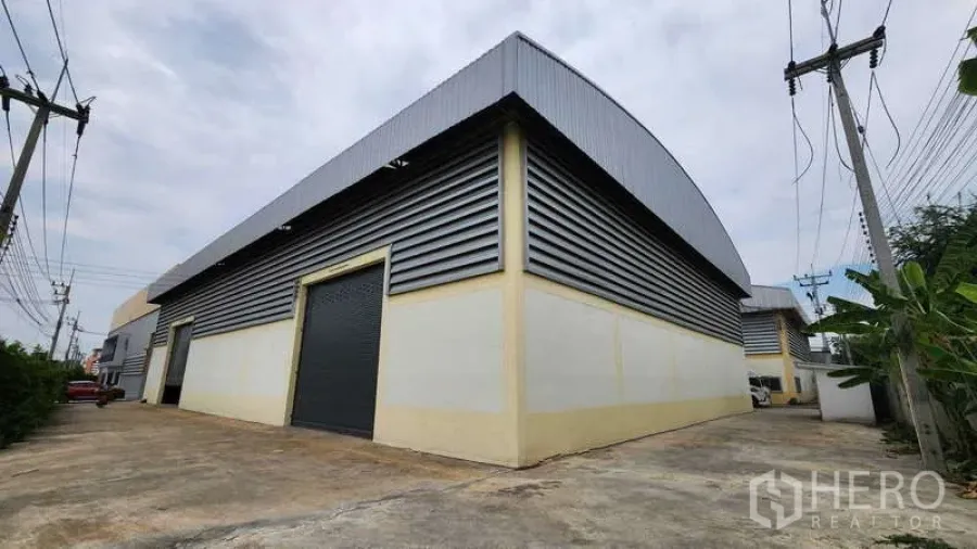 Factory for rent in Ban Phaeo, Samut Sakhon - Factory exterior with corrugated metal cladding, large roller shutters and a wide driveway for container trucks.