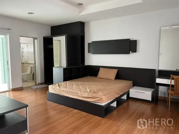 Townhouse for rent in Saphan Sung, Bangkok - Spacious master bedroom with platform bed, built-in storage and access to an ensuite bathroom.