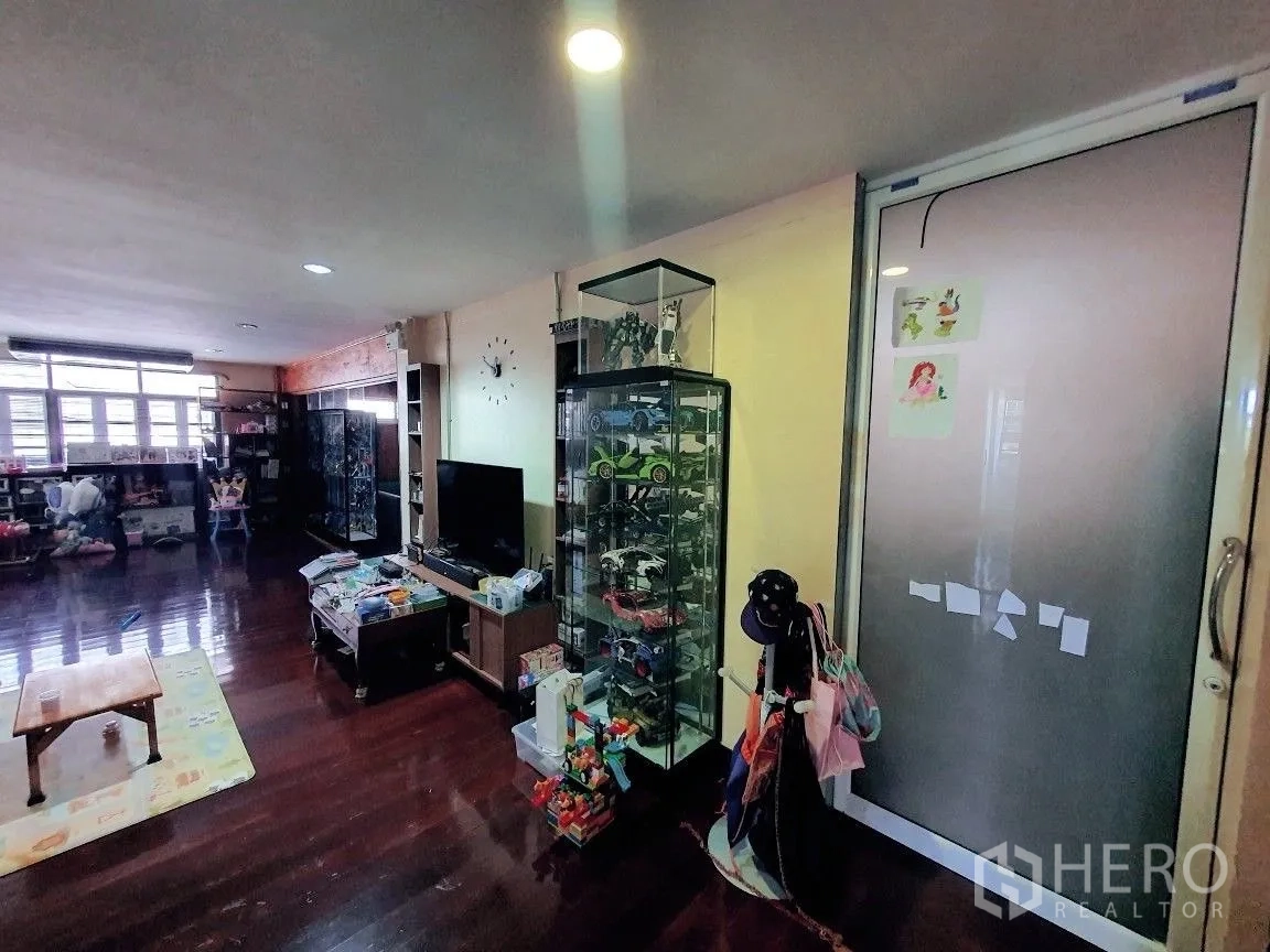 Warehouse for rent in Lam Luk Ka, Pathum Thani - Living area with TV and display cabinets on polished wooden flooring.