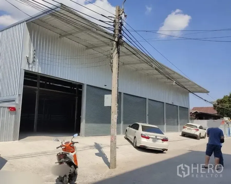 Warehouse for rent in Bang Kapi, Bangkok - Modern metal-clad warehouse exterior with wide driveway and multiple roller shutter bays.