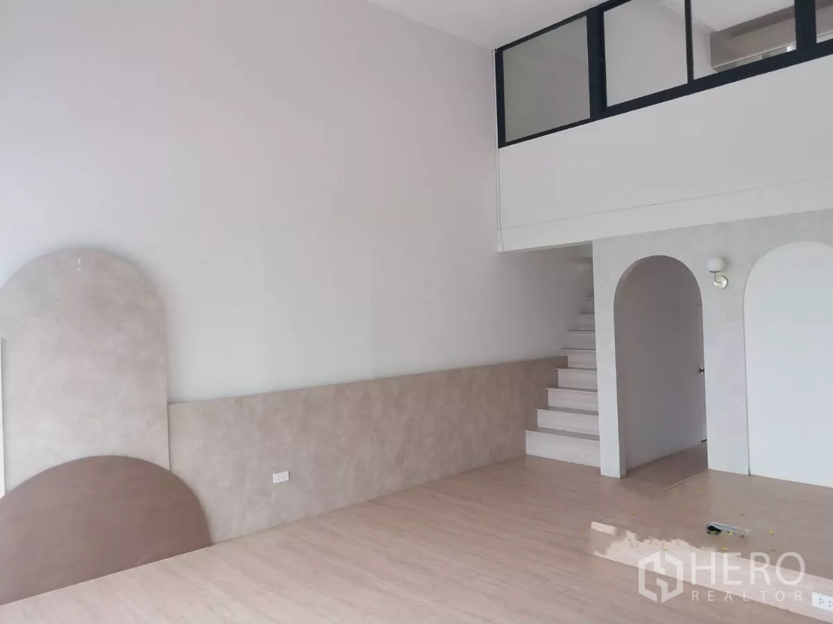 Retail Space for rent - Side angle of the shop interior featuring a mezzanine level and staircase over light wood flooring.