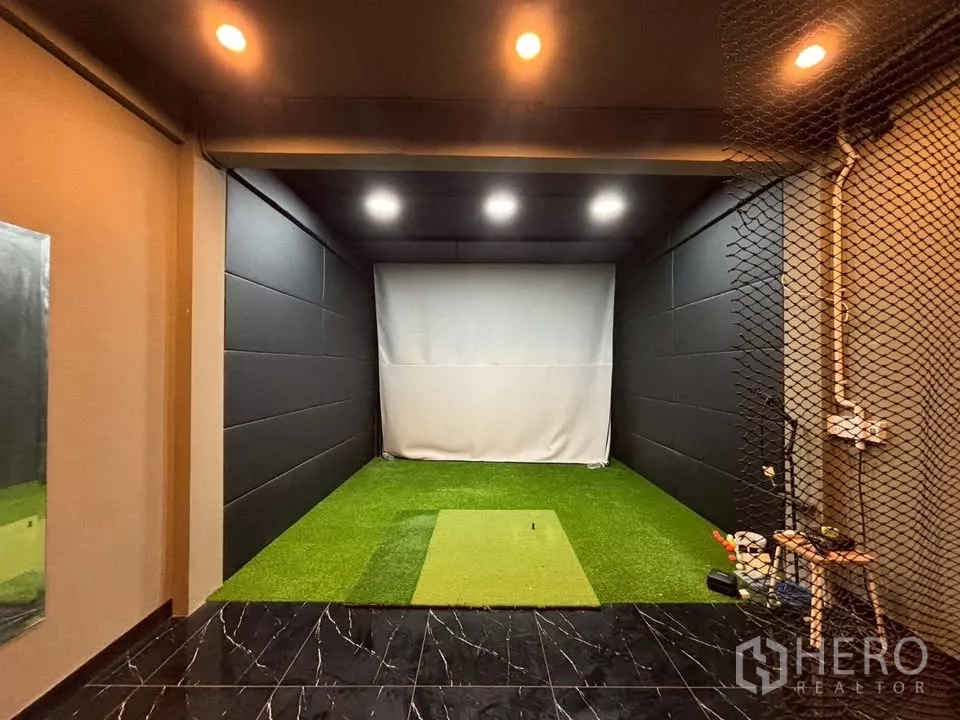Shophouse for rent in Watthana, Bangkok - Indoor golf simulator bay with artificial turf mat, netting and ceiling lights.