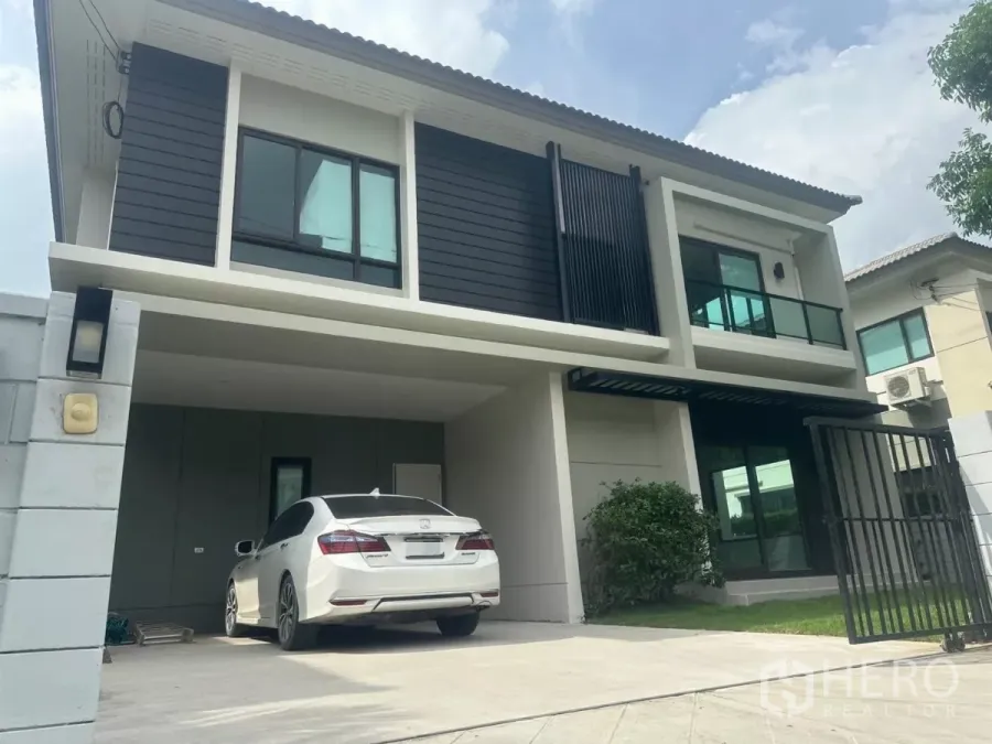 Detached House for sale in Samut Prakan - Two-storey detached house with modern facade, covered two-car carport, gate and small front lawn.