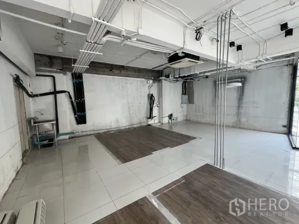 Retail Space for rent - Back service area showing utility pipes, a stainless sink and exposed conduits.