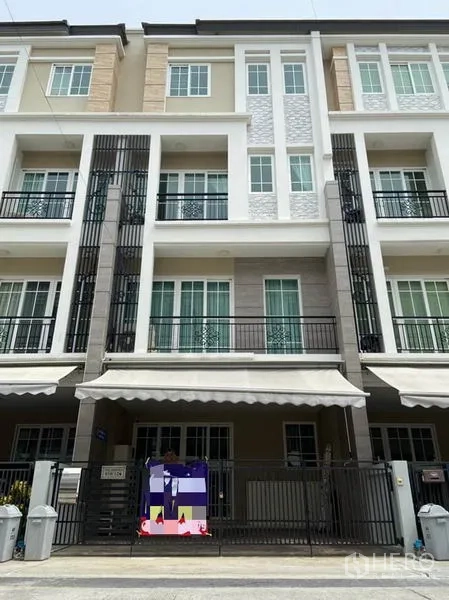 ทาวน์เฮาส์ ให้เช่าในBang Na, Bangkok - ด้านหน้าทาวน์เฮ้าส์สไตล์โมเดิร์นหลายชั้นพร้อมระเบียงและโทนสีเข้ม ในเขตบางนา กรุงเทพฯ