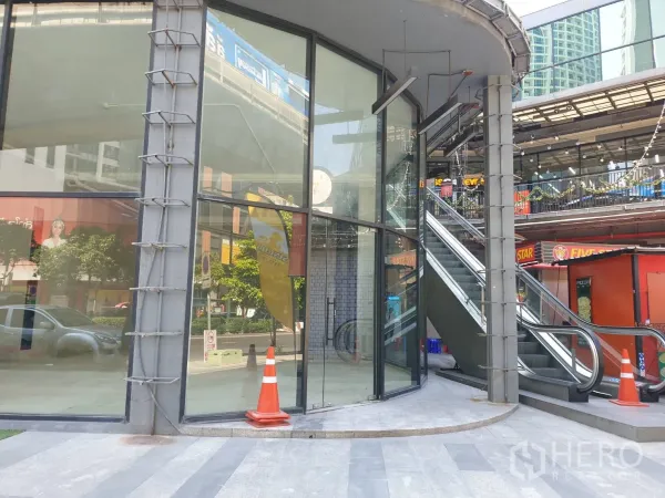 Retail Space for rent in Watthana, Bangkok - Corner retail storefront with curved full‑height glazing beside an outdoor escalator in a lifestyle complex.