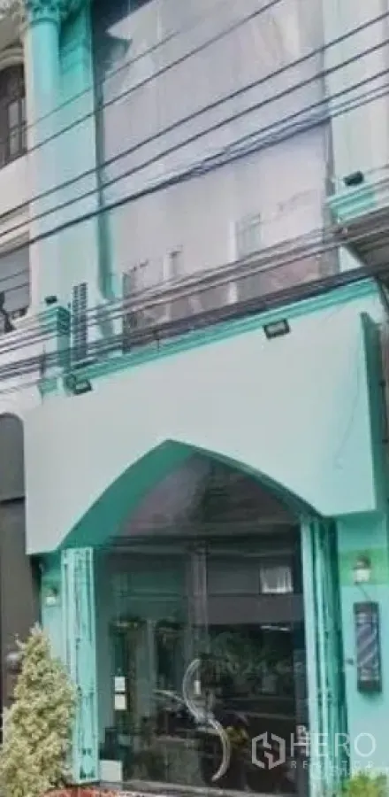 Shophouse for rent in Watthana, Bangkok - Street-facing mint-green shophouse with large glass storefront and arched entrance near BTS Thong Lo in Watthana, Bangkok.