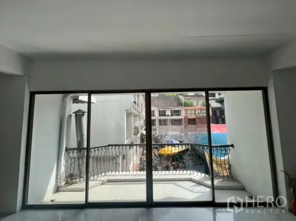 Retail Space for rent in Pathum Wan, Bangkok - Room with sliding glass doors opening to a small balcony overlooking nearby shophouses and market awnings.