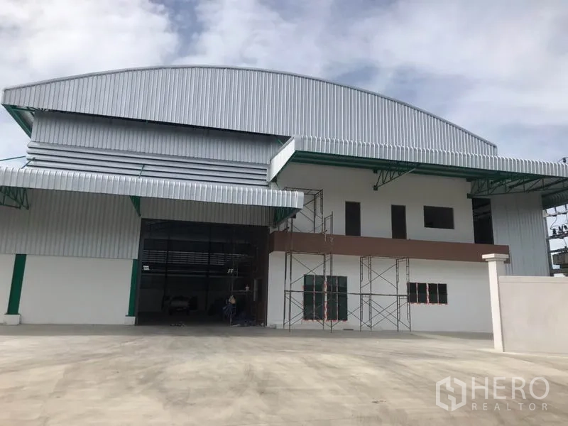 工厂 出租或出售在Mueang Samut Sakhon, Samut Sakhon - 厂房正立面，宽幅卷帘门与两层办公楼。