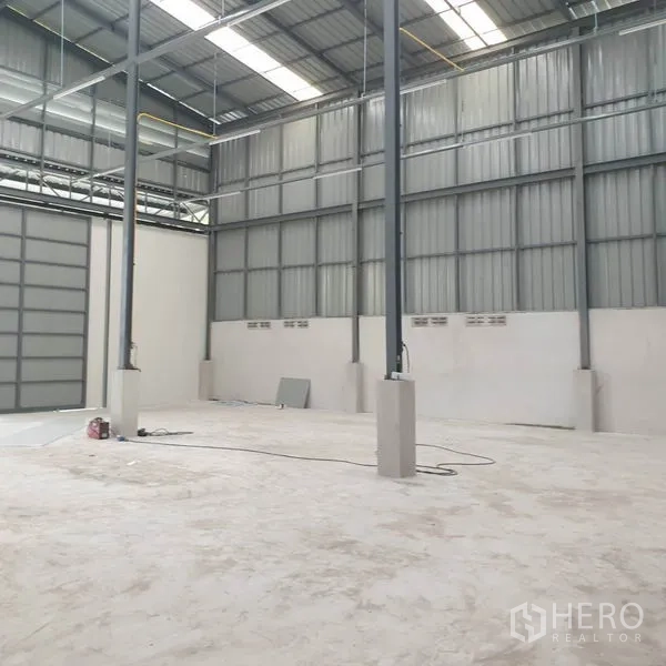 Warehouse for rent in Khlong Toei, Bangkok - Open storage bay featuring steel beams and a large roller shutter door.