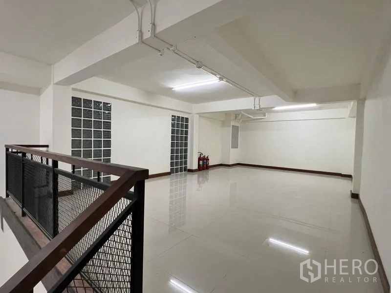 Shophouse for rent in Khlong Toei, Bangkok - Spacious mezzanine area with glass-block windows, overhead lighting and fire extinguishers.