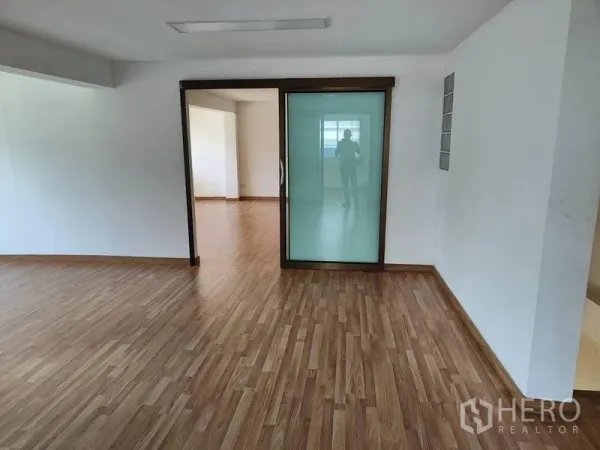 Factory for sale in Sai Noi, Nonthaburi - Open office space with a frosted sliding glass door and wood floors.