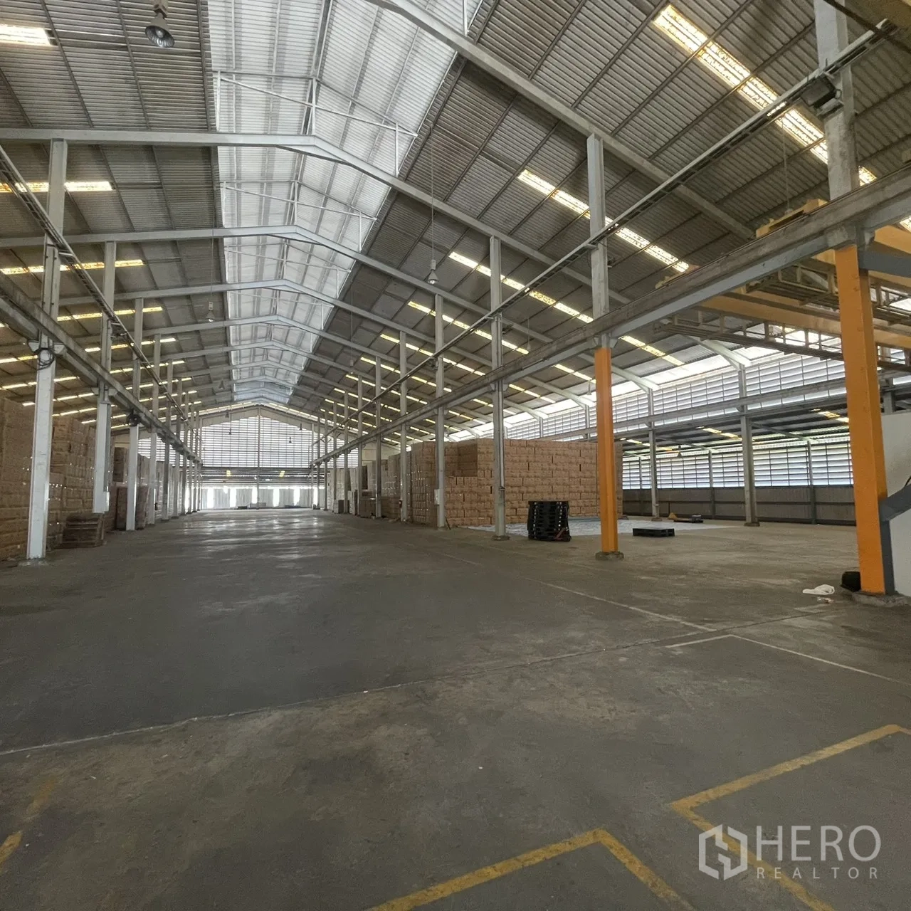 Factory for rent in Khlong Toei, Bangkok - Spacious warehouse interior with high gabled roof, skylights, and durable concrete floor.