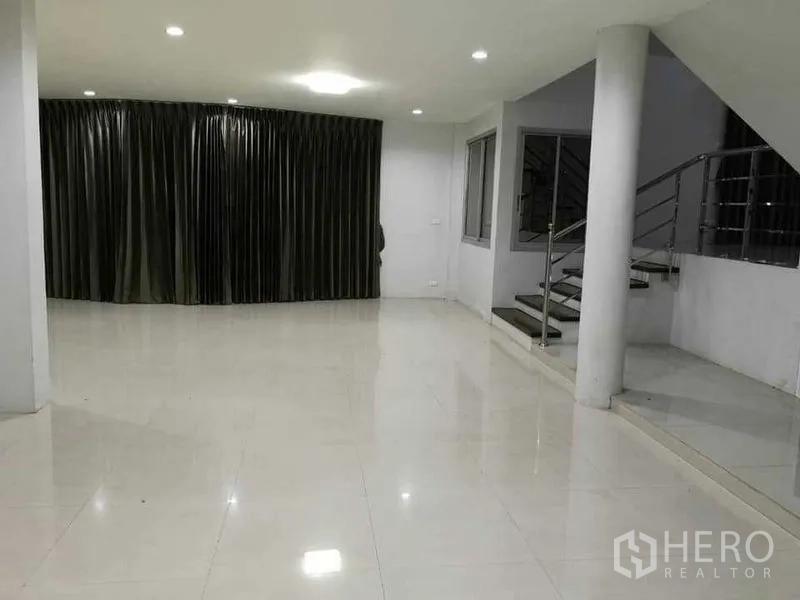 Home Office for rent in Khlong Toei, Bangkok - Spacious living room with full-length curtains and a staircase.