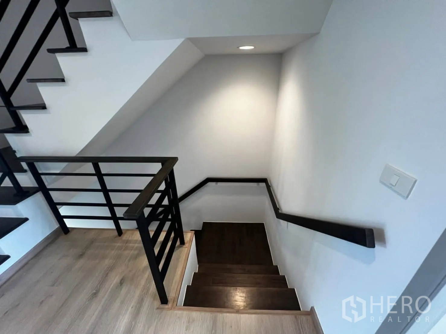 Townhouse for rent in Bang Khen, Bangkok - Staircase with dark wood steps and black handrails connecting the levels.