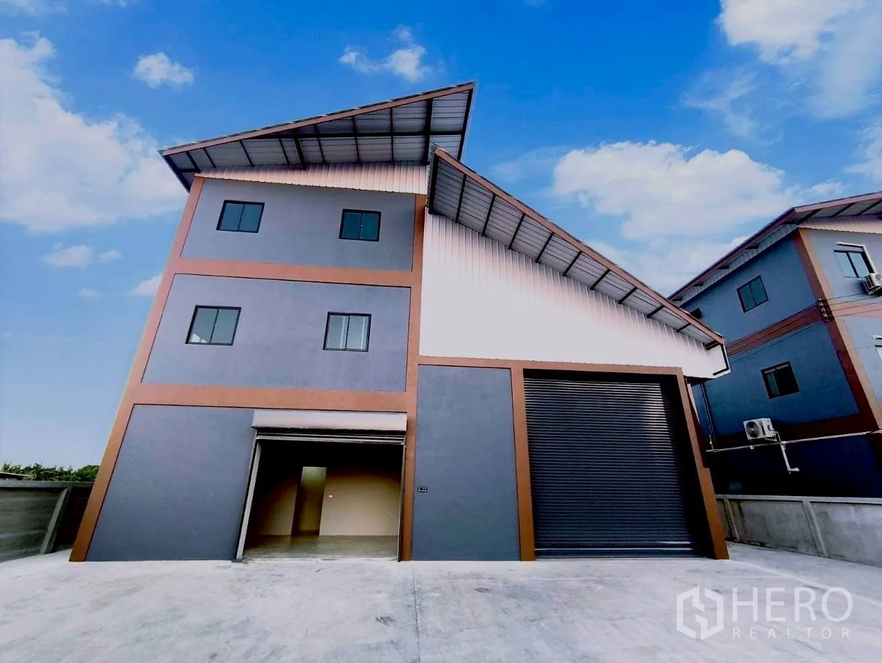 Warehouse for rent in Mueang Nonthaburi, Nonthaburi - Front view of the warehouse showing two roller shutter doors and driveway.