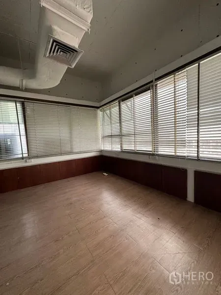 Office Space for rent in Watthana, Bangkok - Corner office with wood floors, wraparound windows, and venetian blinds for light control.