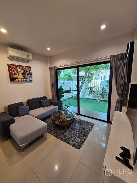 Detached House for rent in Bang Phli, Samut Prakan - Wide view of the living area with sofa, rug and lawn outlook.