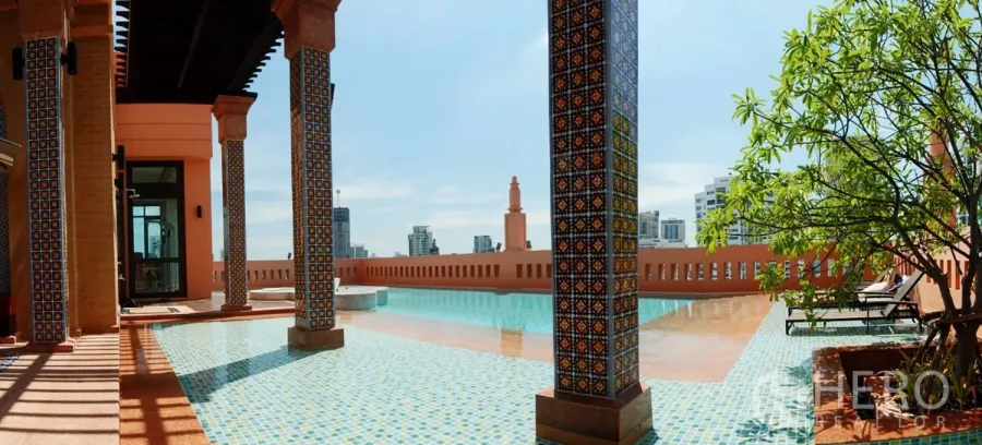 Condominium for rent in Khlong Toei, Bangkok - Rooftop swimming pool with patterned columns, sun loungers, and panoramic Bangkok skyline views.