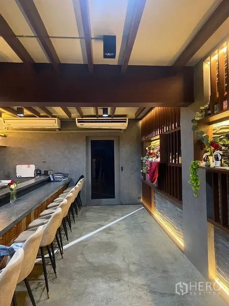 店屋 出租 - 长形酒吧休闲区，混凝土台面、外露梁与暖色灯光。