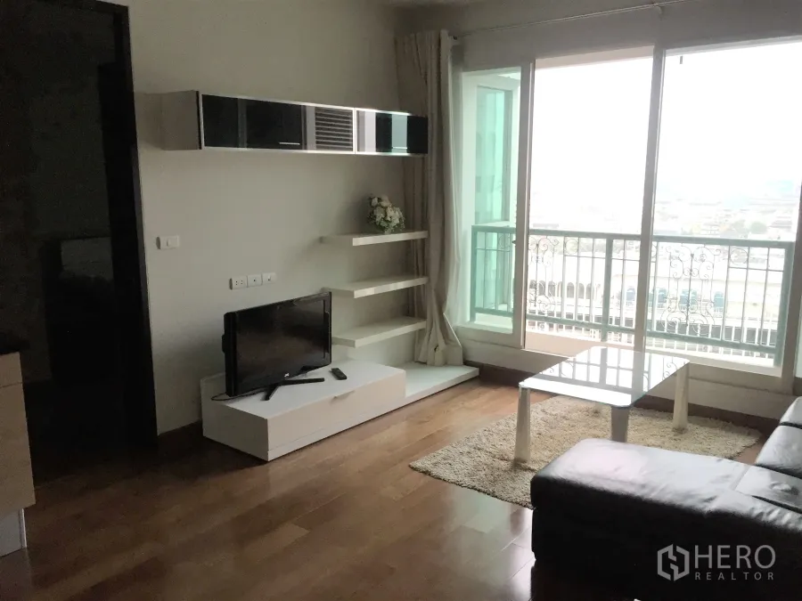 Condominium for rent or sale in Pathum Wan, Bangkok - Bright living room with floor-to-ceiling windows, balcony and city view, wood floors, TV console and sofa.