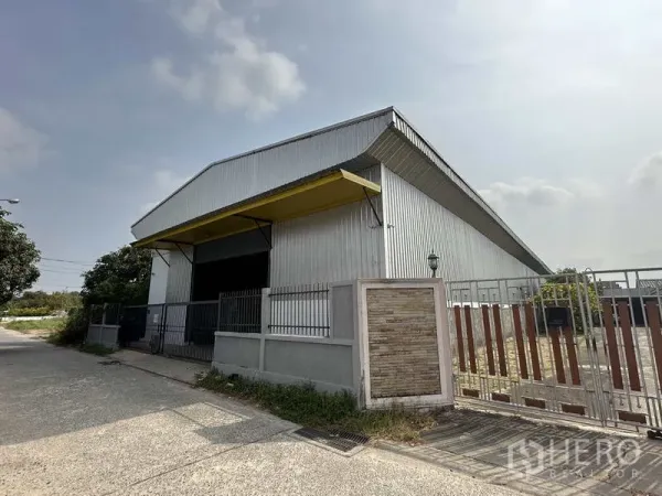 Warehouse for rent in Bang Khen, Bangkok - Metal-clad warehouse exterior with yellow loading canopy and secure gate on a quiet Bang Khen street.