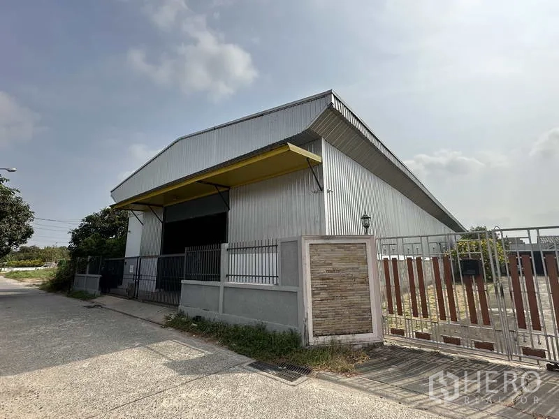 Warehouse for rent in Bang Khen, Bangkok - Metal-clad warehouse exterior with yellow loading canopy and secure gate on a quiet Bang Khen street.
