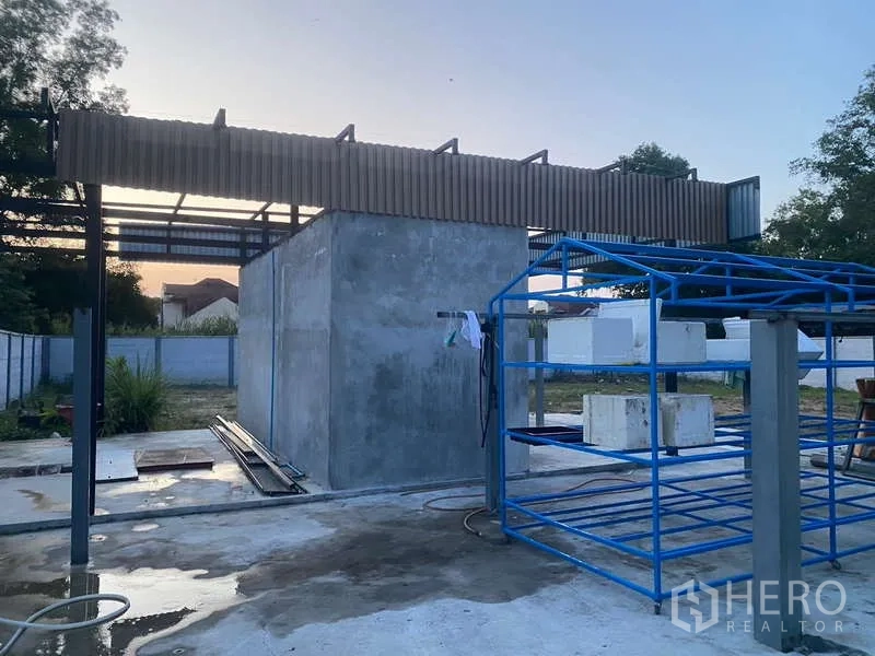 Warehouse for rent or sale in Nong Chok, Bangkok - Outdoor utility area featuring a concrete service room and metal racks beside the warehouse.