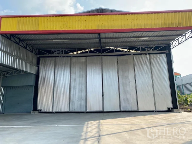 Warehouse for rent in Lat Krabang, Bangkok - Front view of Lat Krabang warehouse with wide folding metal doors, covered loading bay, and concrete driveway.