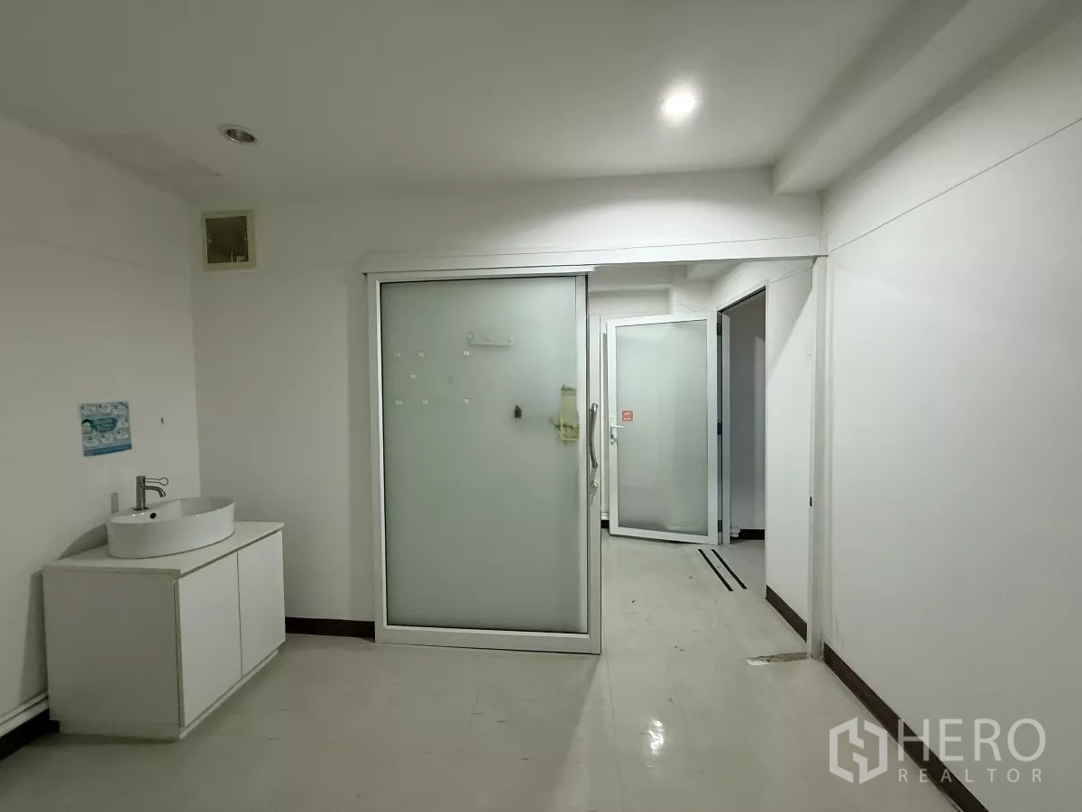 Office Space for rent in Din Daeng, Bangkok - Hallway workspace with frosted glass door, white storage cabinet and bright ceiling lights.