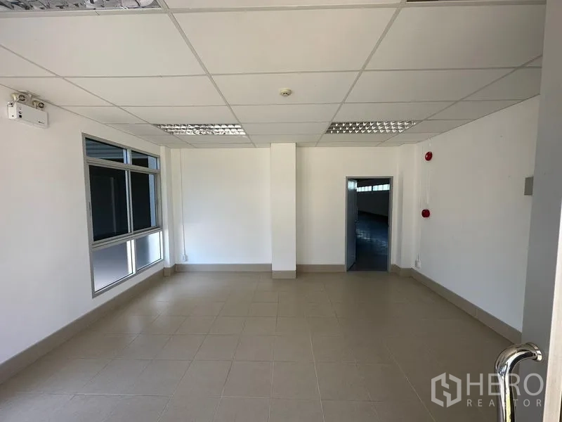 Factory for rent in Bang Bo, Samut Prakan - Compact tiled office room with grid ceiling and a window looking into the warehouse.