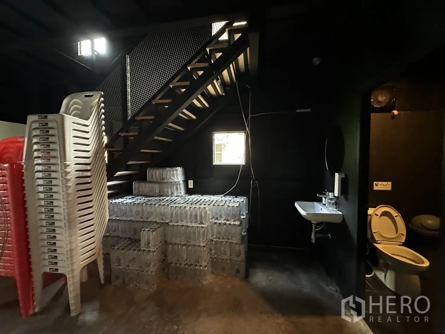 Warehouse for rent in Phra Khanong, Bangkok - Ground-floor utility area showing staircase, wall-mounted sink, and bathroom access.
