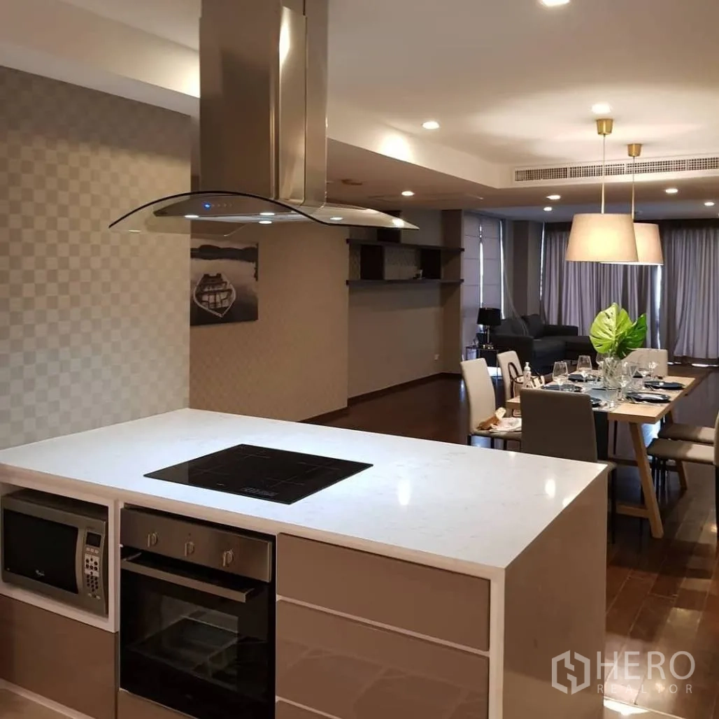 Condominium for rent or sale in Pathum Wan, Bangkok - Open-plan kitchen flowing to dining and lounge, highlighted by an island cooktop, oven, and modern fixtures.