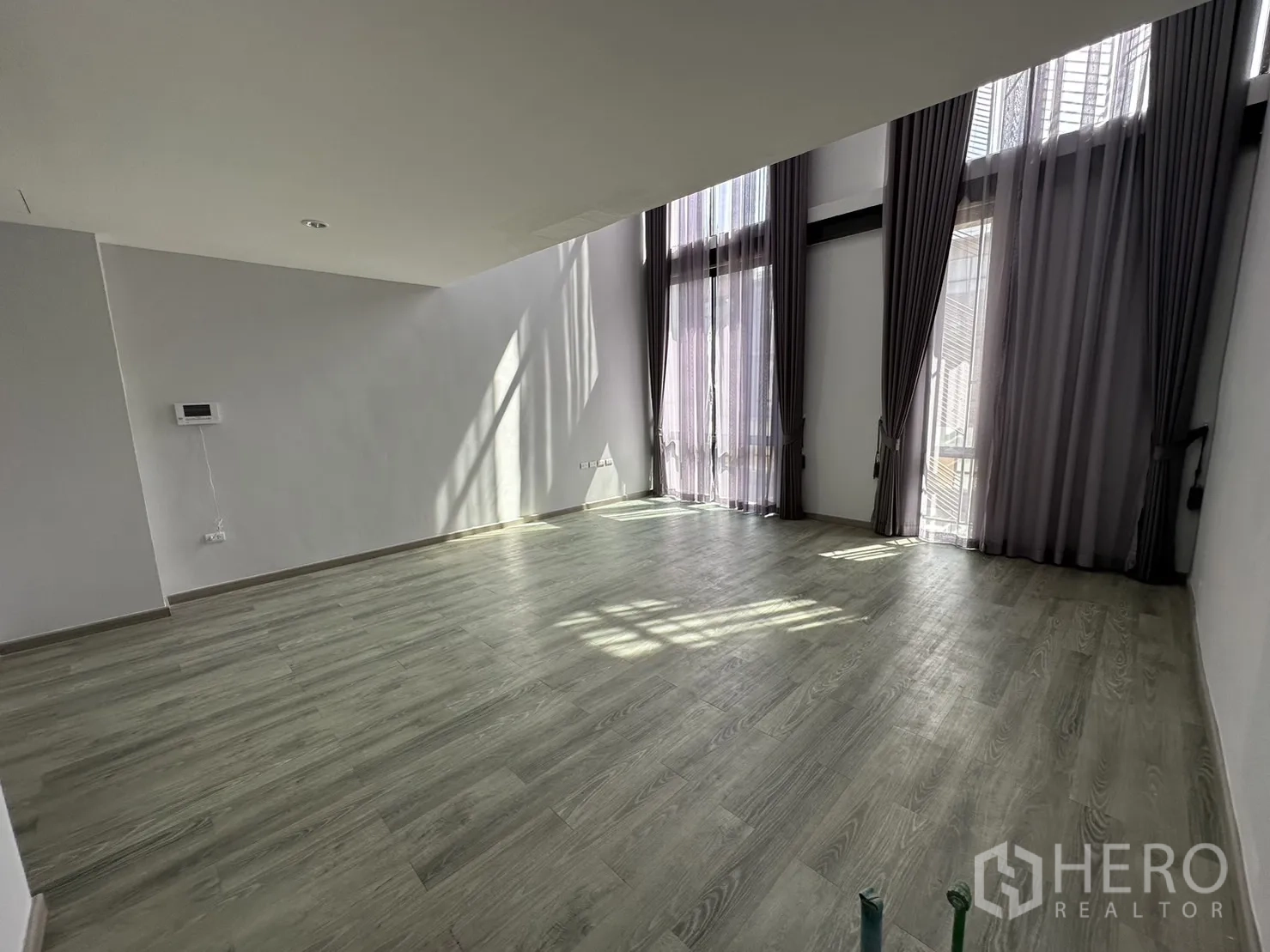 Home Office for rent or sale in Suan Luang, Bangkok - Bright room with tall glass doors, sheer curtains and wood-look flooring.