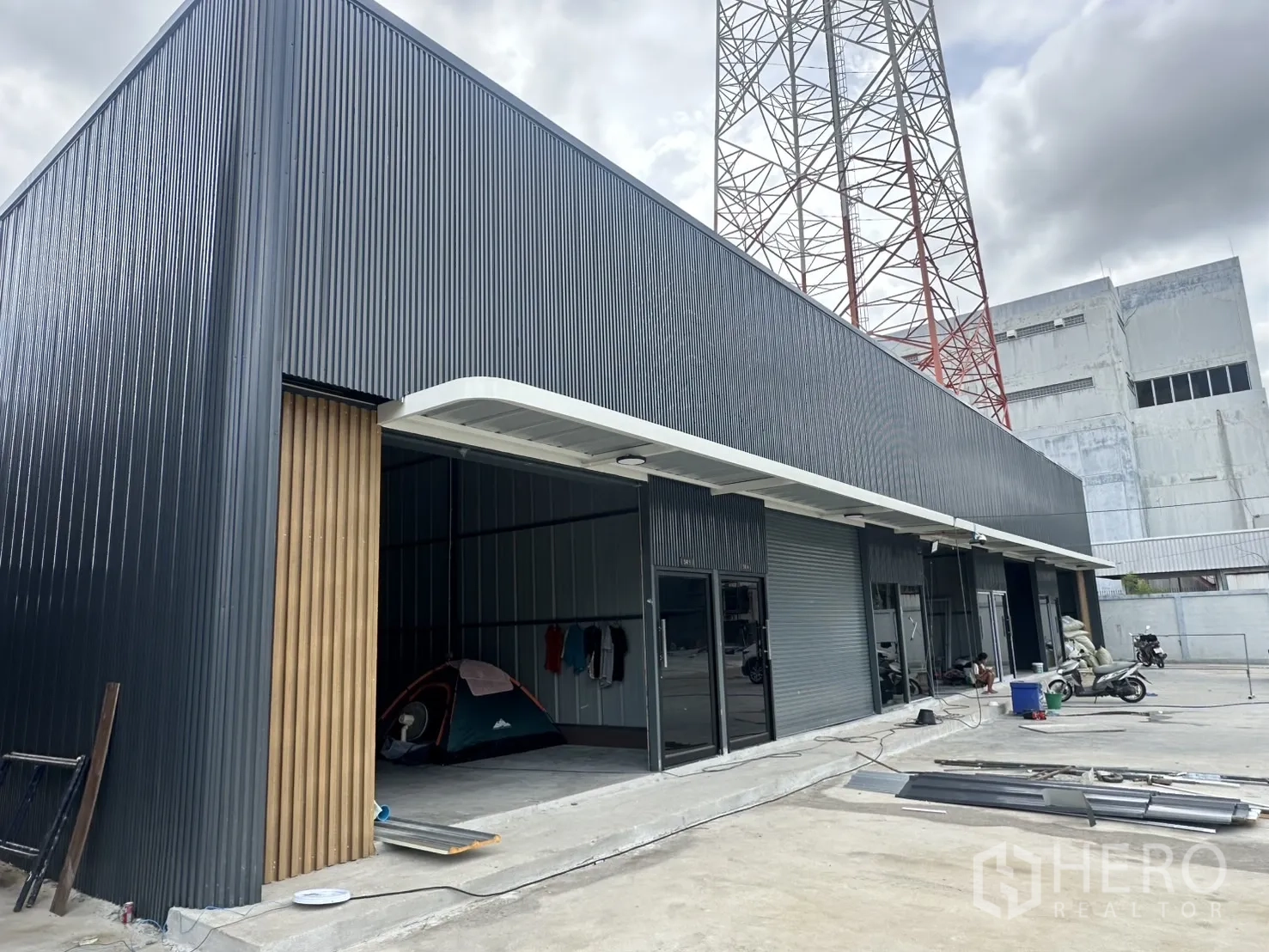 Warehouse for rent in Suan Luang, Bangkok - Contemporary row of warehouse units with roller shutter doors and a covered loading apron.