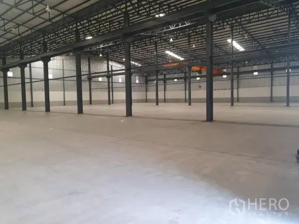 Factory for rent in Mueang Samut Prakan, Samut Prakan - Open-span warehouse floor with steel columns and skylight panels.