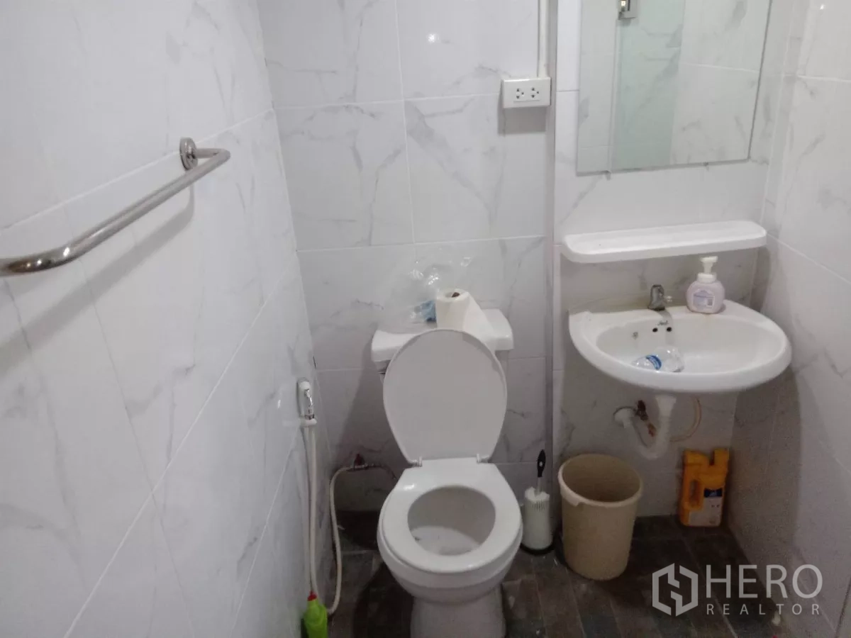 Detached House for rent in Phaya Thai, Bangkok - Compact white-tiled bathroom with toilet, sink and bidet spray.