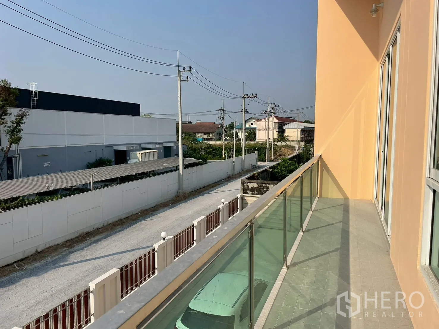 Factory for sale in Sam Phran, Nakhon Pathom - Glass-railed balcony of the factory overlooking a quiet service road and nearby warehouses.