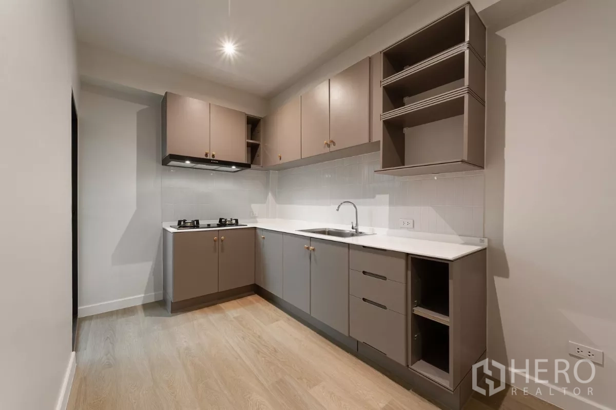 Townhouse for rent in Watthana, Bangkok - Secondary kitchen with L-shaped cabinets, gas hob and solid-surface counters.