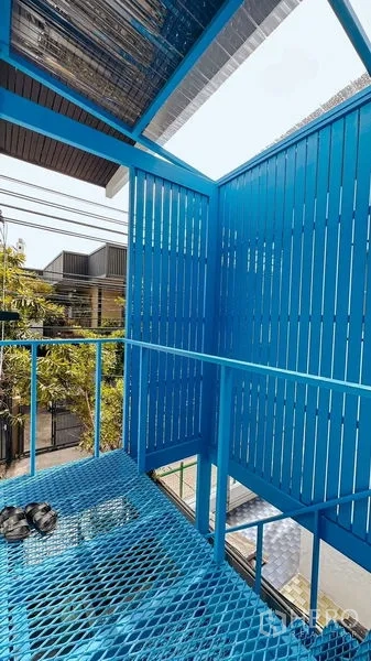 Home Office for rent in Watthana, Bangkok - Covered balcony area with blue metal railing and louvered panels overlooking the street.