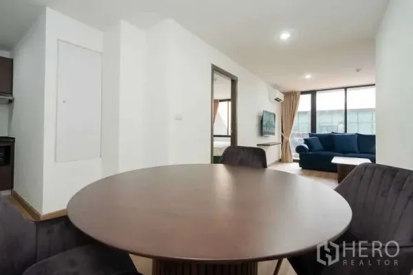 Apartment for rent in Khlong Toei, Bangkok - Bright dining area with a round table facing the living room and bedroom doorway.